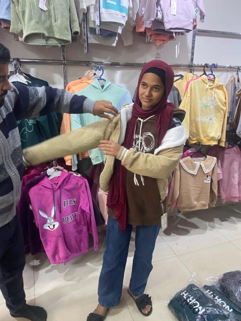 طفلة من أطفال غزة الأيتام تستلم كسوة شتوية مقدمة من جمعية التحالف للإغاثة والتنمية بعد تضررها من حرب غزة