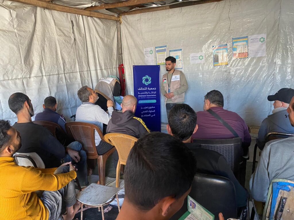 تعزيز الوعي الصحي للرجال في غزة | جلسة توعوية داخل مخيم المنطار بدعم جمعية التحالف 3 مشاركون يتابعون جلسة توعية صحية للرجال داخل مخيم المنطار في غزة